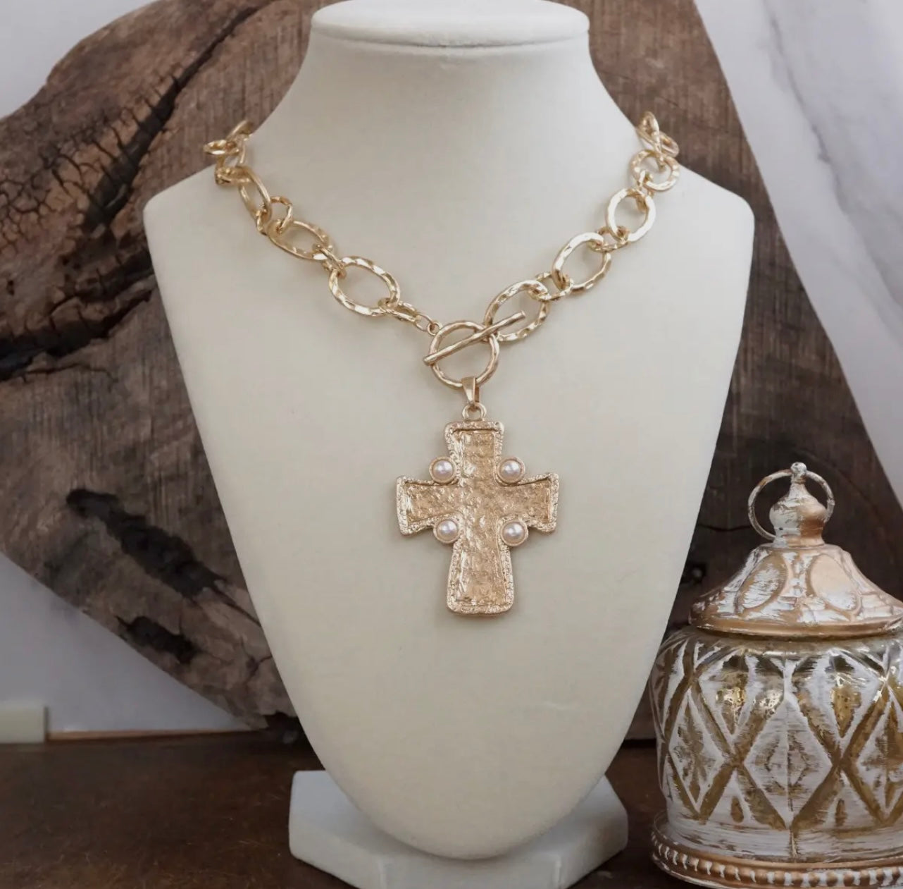 Gold chain necklace with a cross pendant on a mannequin bust.