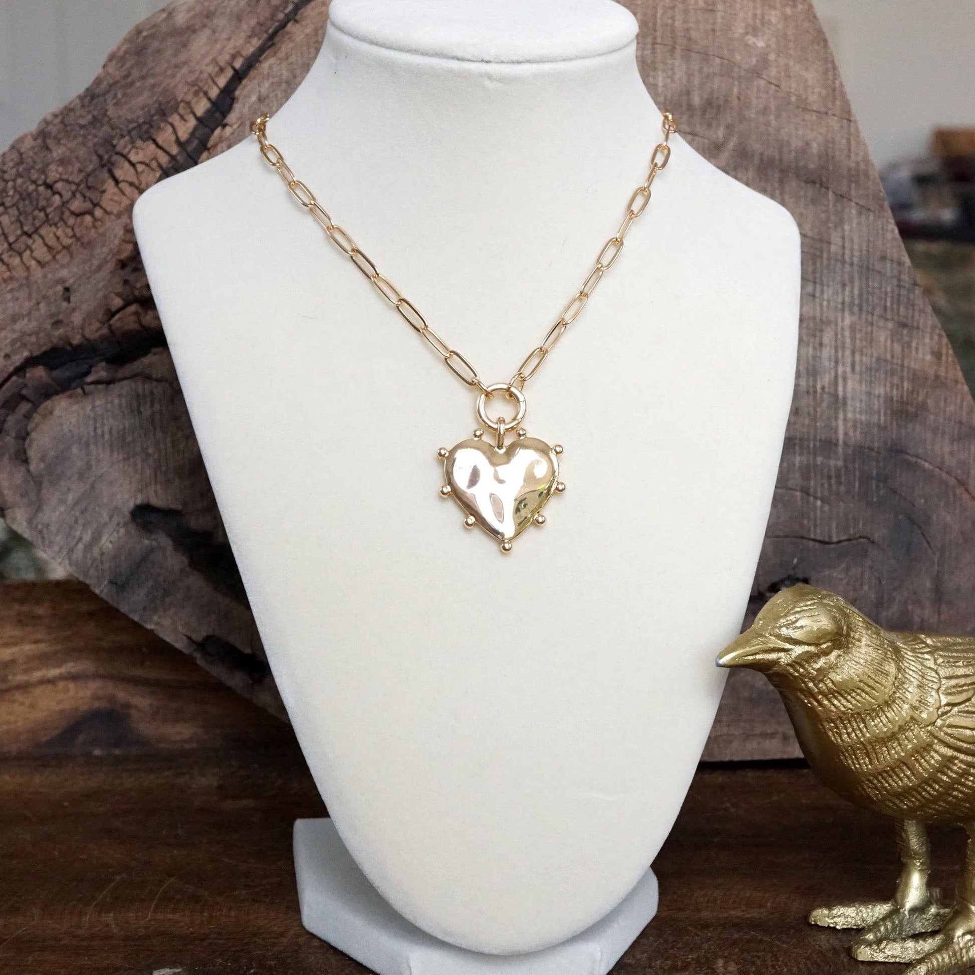 Gold heart-shaped necklace on a mannequin bust, link chain 
