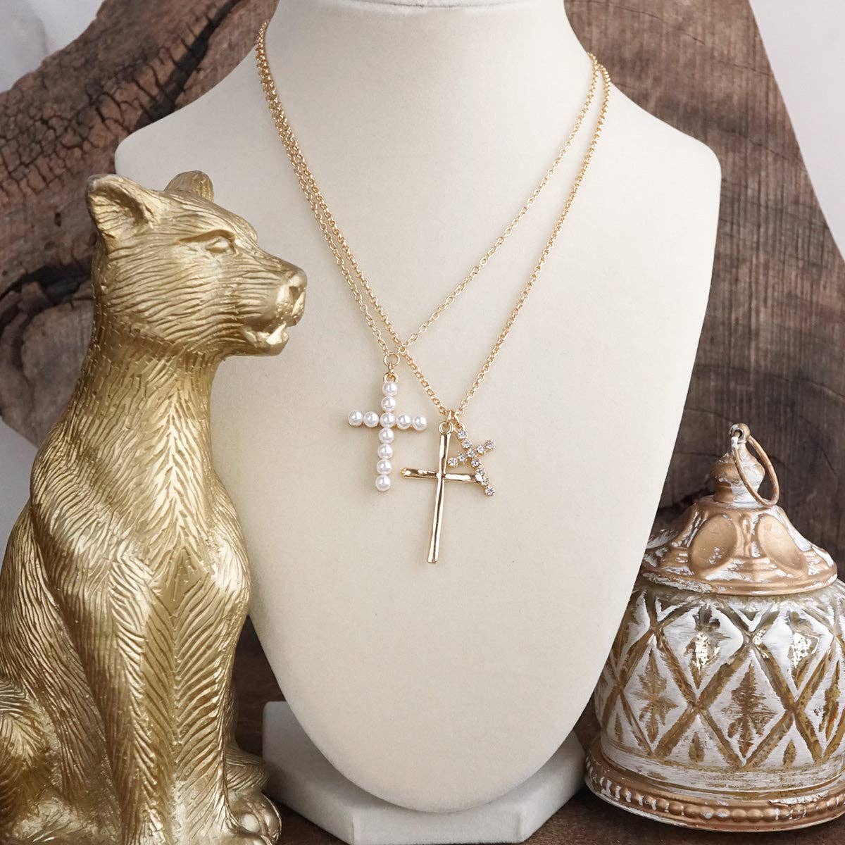 Layered gold necklace with three cross pendants on a mannequin bust