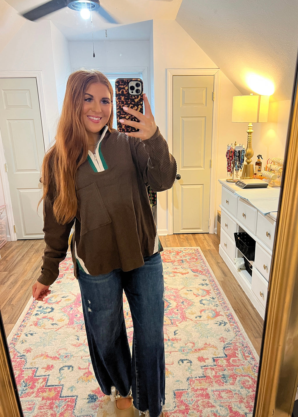 Chocolate brown quarter zip with green and white contrast zipper and side slit details. Front pocket 